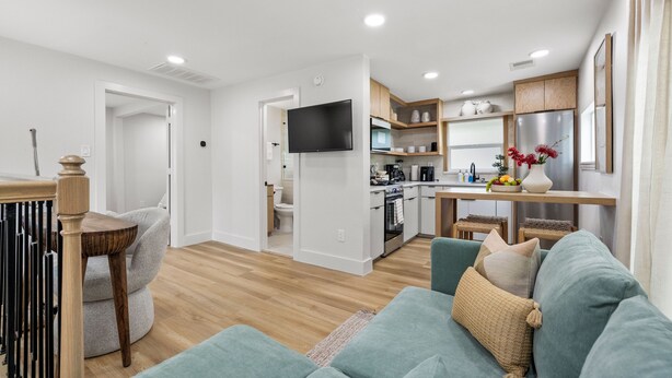 A modern living room with a sofa, a dining table, and a kitchen area in the background.