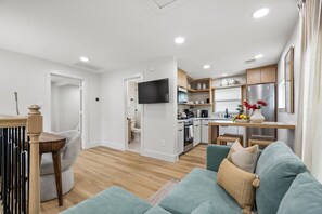 Una sala de estar moderna con un sofá, una mesa de comedor y una cocina al fondo.