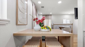A dining area with a wooden table, woven chairs, and a vase with flowers.