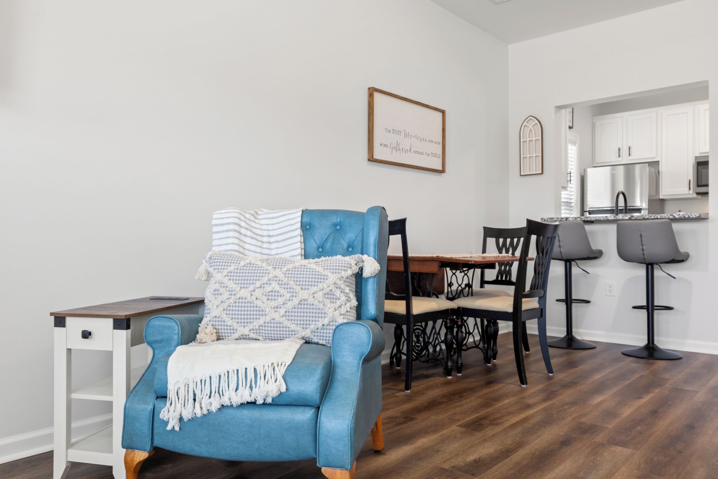 Un coin repas avec un fauteuil bleu, une table en bois et des chaises noires.