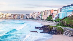 A coastal cityscape with a beach, buildings, and a rocky shoreline.