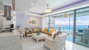 A modern living room with a sofa set, a coffee table, and a kitchen area with a stove.