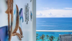 A room with a view of the ocean and a balcony with a pool.