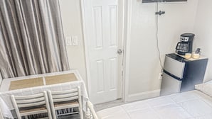 A bedroom with a bed, a desk with a chair, a television mounted on the wall, and a coffee maker on a cabinet. - Cozy and Charming Studio in Fort Lauderdale (Fort Lauderdale)