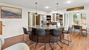 A modern kitchen with a central island, bar stools, pendant lighting, and a view of the outdoors. - The Peak: Hot tub + Mt. Views (Packwood)