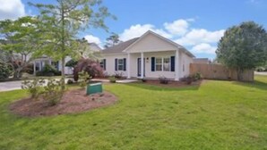 A single-story house with a front porch, a small front yard, and a tree.