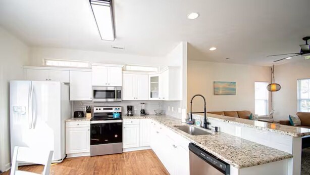 A modern kitchen with white cabinets, stainless steel appliances, and a granite countertop.
