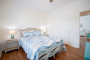 Un dormitorio con una cama, dos mesitas de noche y una puerta.