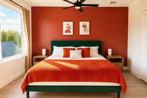 A bedroom with a bed, two bedside tables, a ceiling fan, and artwork on the wall.