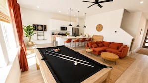 Una sala de estar moderna con mesa de billar, un sofá y comedor.