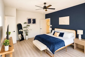 A bedroom with a bed, bedside table, lamp, and a ceiling fan.