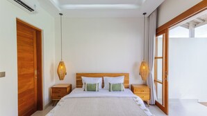 A bedroom with a large bed, wooden headboard, bedside tables, and a view of the outdoors. - Villa Sylvia by Pertama Stay (Kerobokan)
