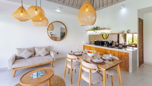 A modern living room with a sofa, dining table, and hanging wicker lights. - Villa Sylvia by Pertama Stay (Kerobokan)