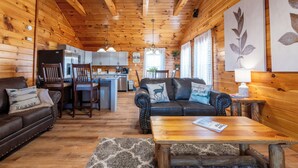 A cozy cabin interior with a living room, dining area, and kitchen.