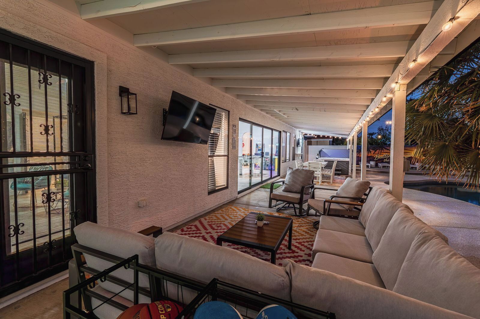 An indoor/outdoor living area with a pool, seating, and a TV.