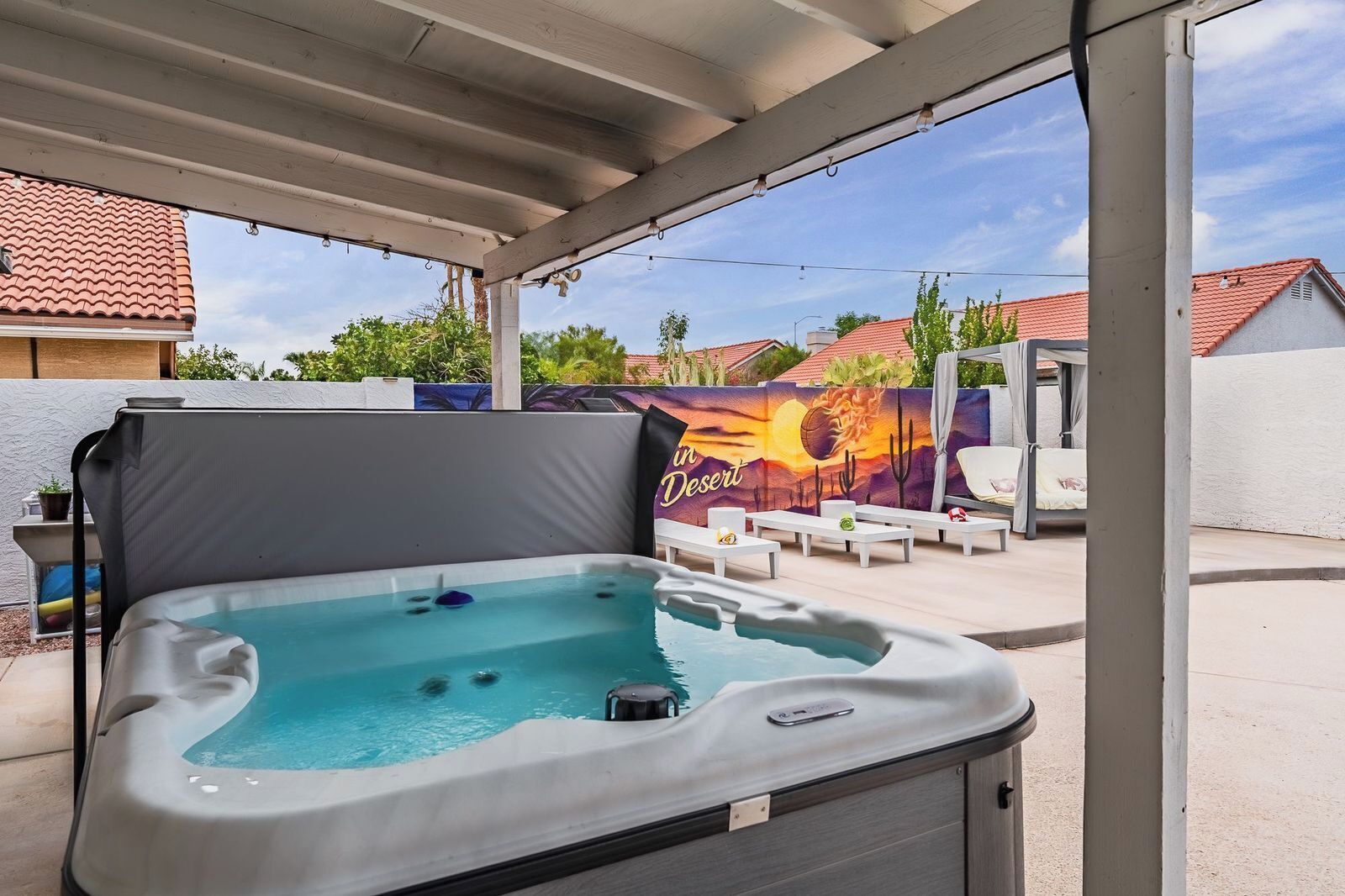 A hot tub under a covered patio with a mural in the background.