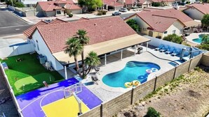 A residential area with a swimming pool, a covered patio, and a basketball court.