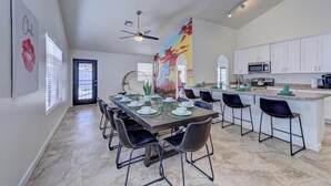 A spacious kitchen with white cabinets, a central island, and a dining area with a long table and chairs.