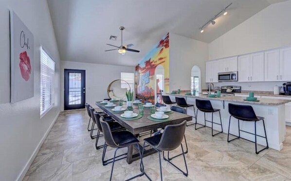 A spacious kitchen with white cabinets, a central island, and a dining area with a long table and chairs.
