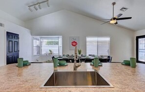 A spacious kitchen with a central island, a ceiling fan, and a dining area with a table set for four.