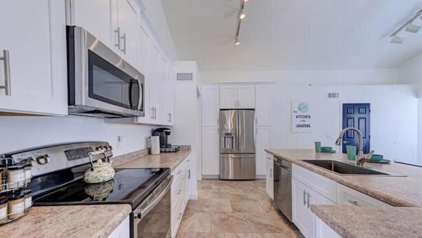 A modern kitchen with white cabinets, stainless steel appliances, and a granite countertop.