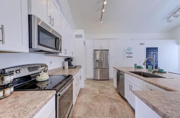 A modern kitchen with white cabinets, stainless steel appliances, and a granite countertop.