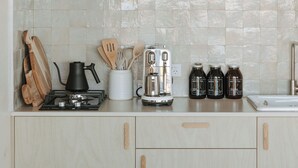 Eine Küche mit hellen Holzschränken, einer Fliesenküchenrückwand und verschiedenen Küchenutensilien wie Wasserkocher, Toaster und Gläsern.