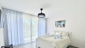 A modern bedroom with a bed, a chair, a ceiling light, and a painting on the wall.