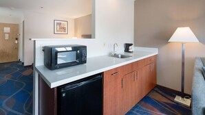 Una kitchenette de hotel compacta con microondas, lavamanos y armario.
