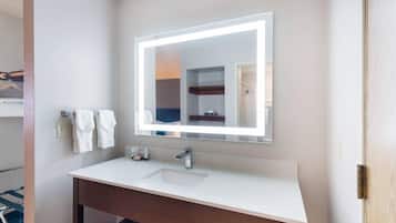 Un baño con un lavamanos blanco, un espejo con luz y un toallero.