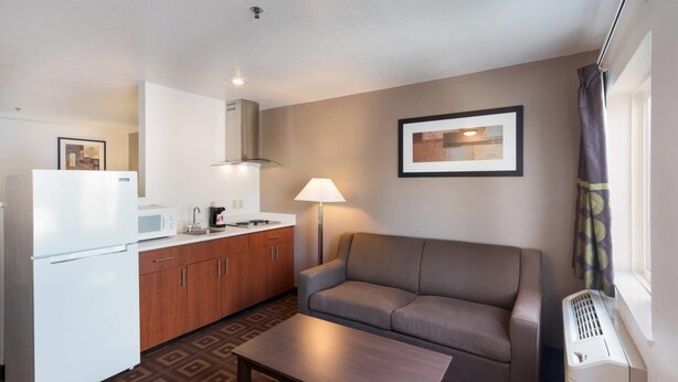 Un espacio habitable compacto con kitchenette, un sofá, una mesa de centro y una ventana con cortinas.