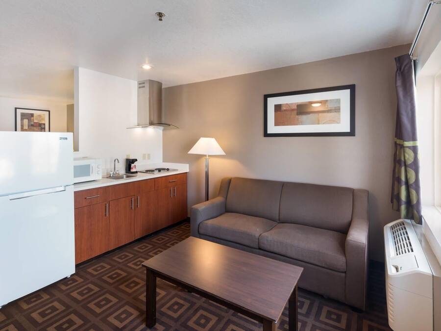 Un espacio habitable compacto con kitchenette, un sofá, una mesa de centro y una ventana con cortinas.