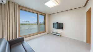A modern living room with a large sliding glass door, a flat-screen TV, a white console table, and a grey sofa. - Yangyang Sunrise Sea Pension (Yangyang)