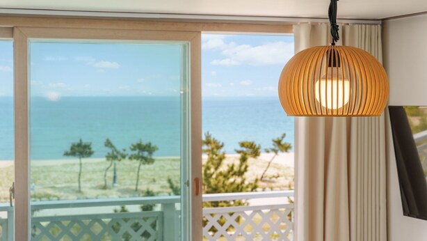 A room with a view of the ocean, a balcony with a white railing, and a hanging lamp. - Yangyang Sunrise Sea Pension (Yangyang)