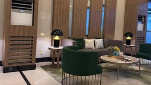 A modern lobby with a sofa, green armchairs, a coffee table, and two lamps. - BAYSHORE RESIDENTIAL RESORT 2 PHASE 1 (Parañaque)