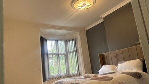 Un dormitorio con una cama grande, una ventana con cortinas y una lámpara de techo.