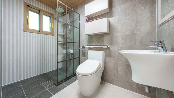 Une salle de bain moderne avec une douche à parois de verre, des toilettes blanches, un lavabo avec un robinet chromé et une fenêtre avec un cadre en bois.