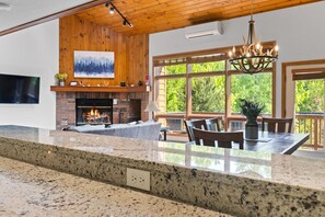 Un espacio habitable amplio con chimenea, ventanas grandes y comedor con encimera de granito.