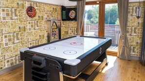 A room with a pool table, a dartboard, and a large window with curtains. - Sampford Hideaway Retreat (Little Sampford)