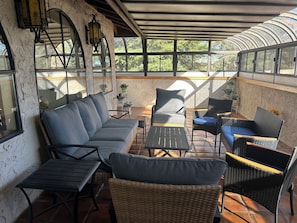 Un patio al aire libre con un sofá, sillas y mesas.