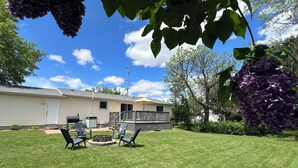 A backyard with a barbecue area, a deck, and a house with a white exterior. - Charming 3 Bedroom 2.5 bathroom finished basement, Huge yard and Charcoal grill (Baraboo)
