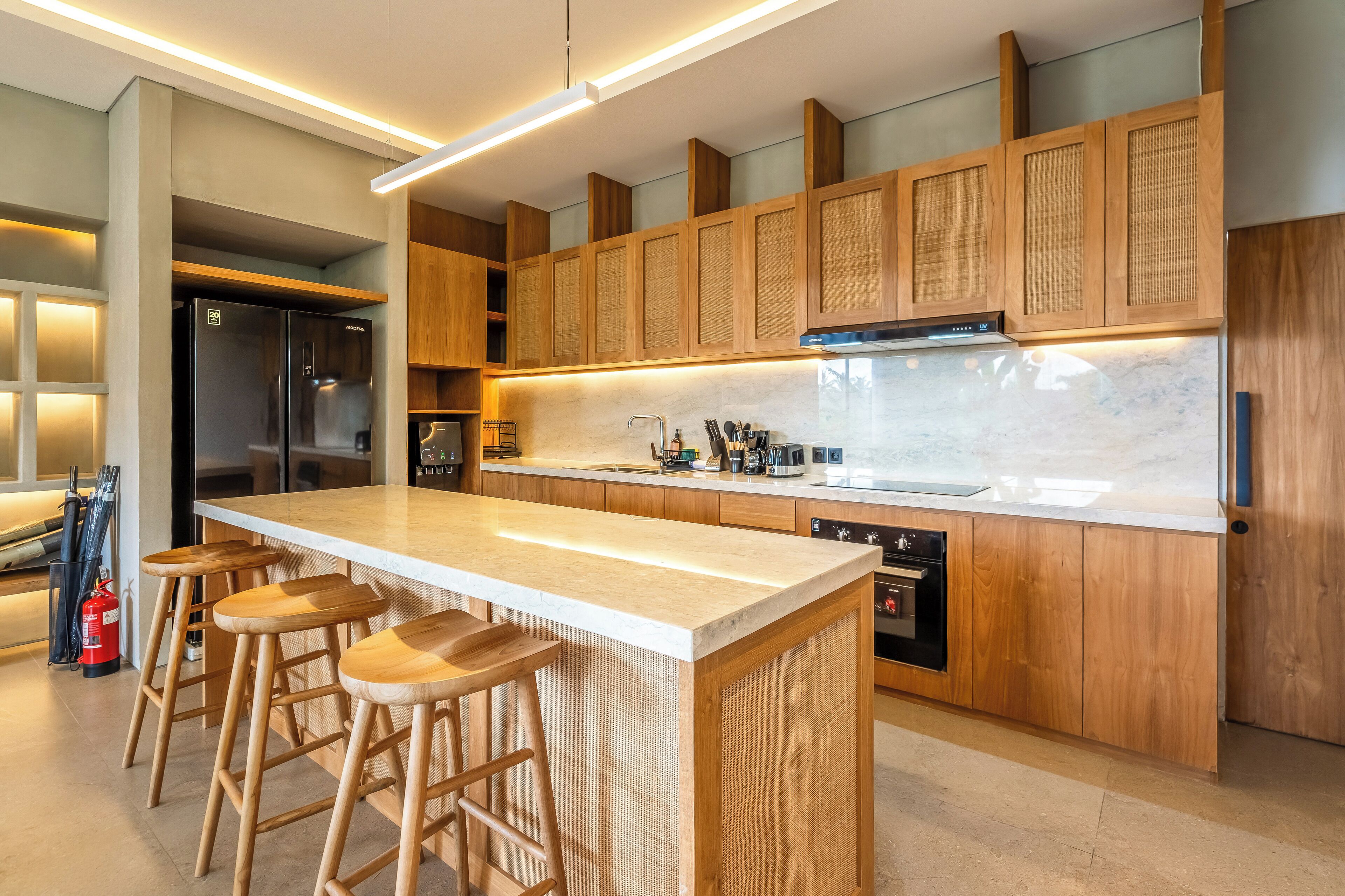 Una cocina moderna con una isla grande, armarios de madera y un refrigerador de acero inoxidable.