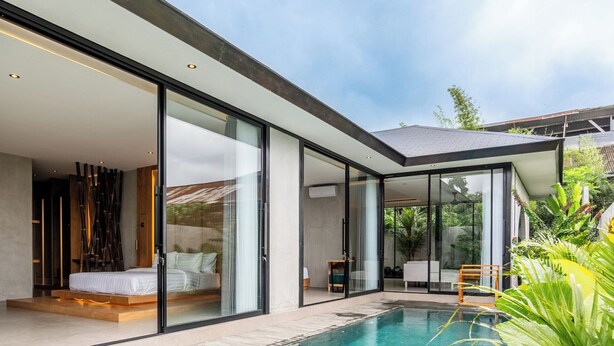 A modern house with a swimming pool, large glass doors, and a wooden deck. - Titi House Villa By Betterplace (Ubud)