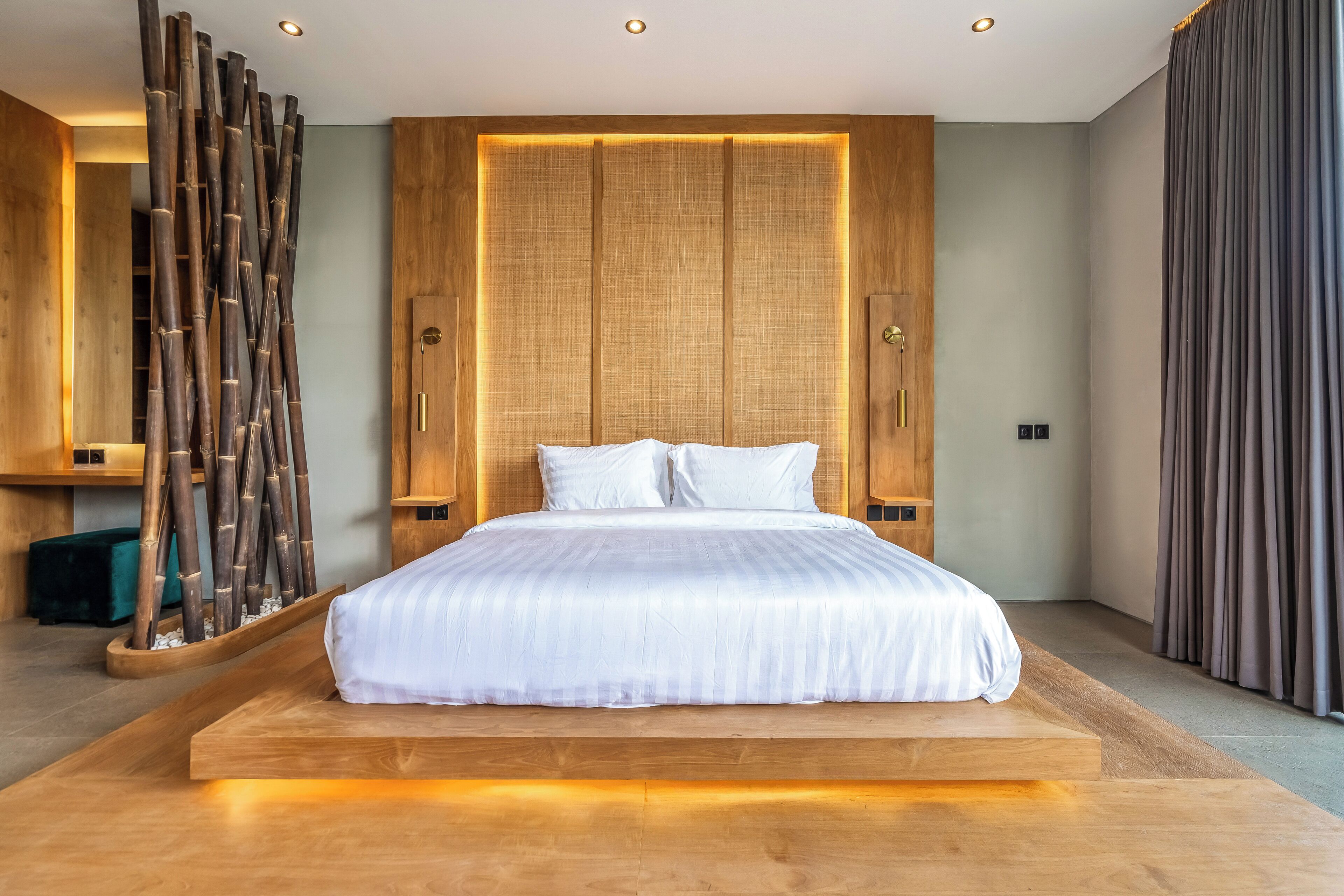 Un dormitorio moderno con una cama grande, cabecera de madera e iluminación ambiental.