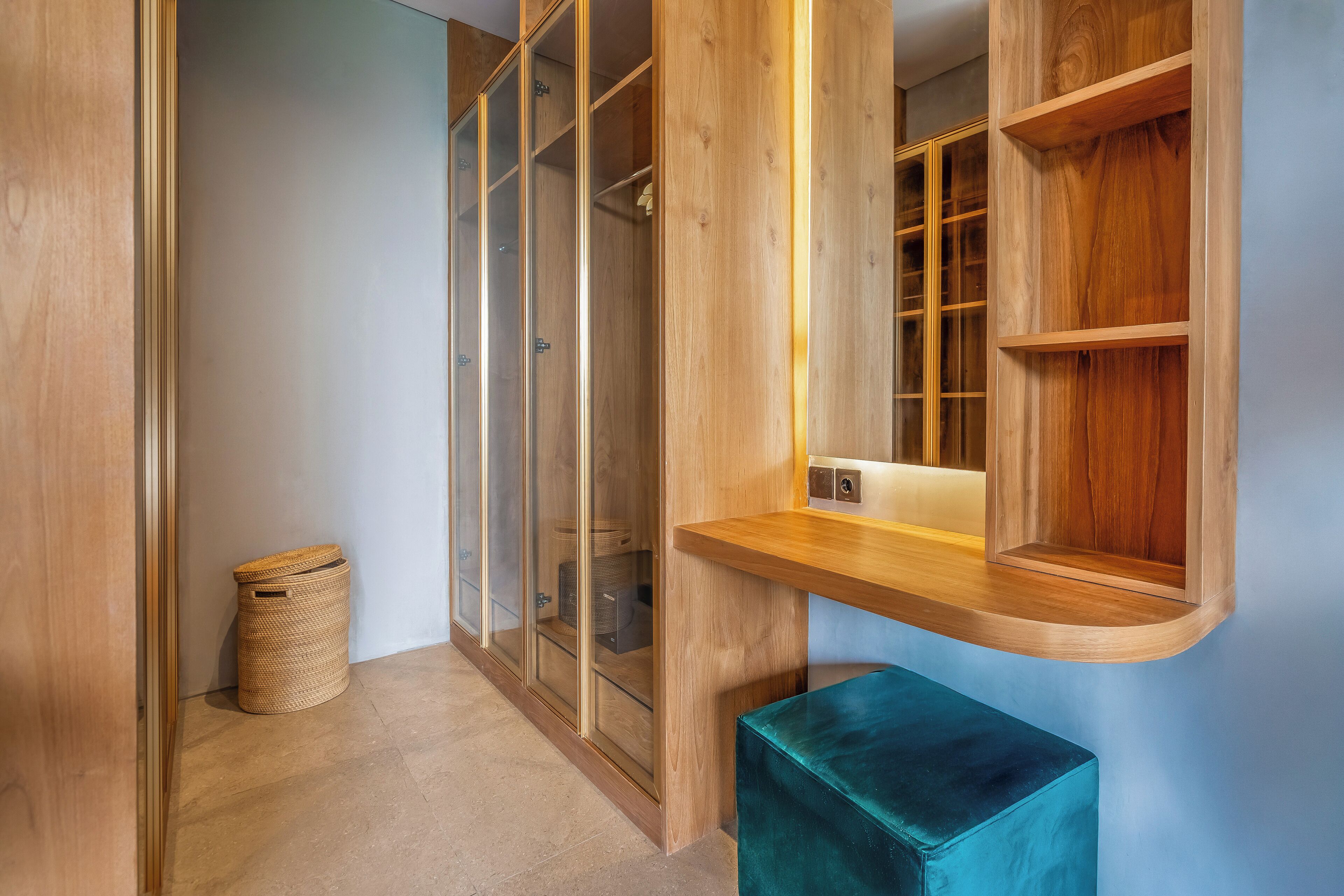 A modern interior with a wooden wardrobe, a woven basket, and a teal bench.
