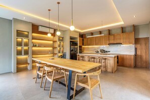 A modern kitchen with a central island, wooden cabinets, and pendant lighting. - Titi House Villa By Betterplace (Ubud)