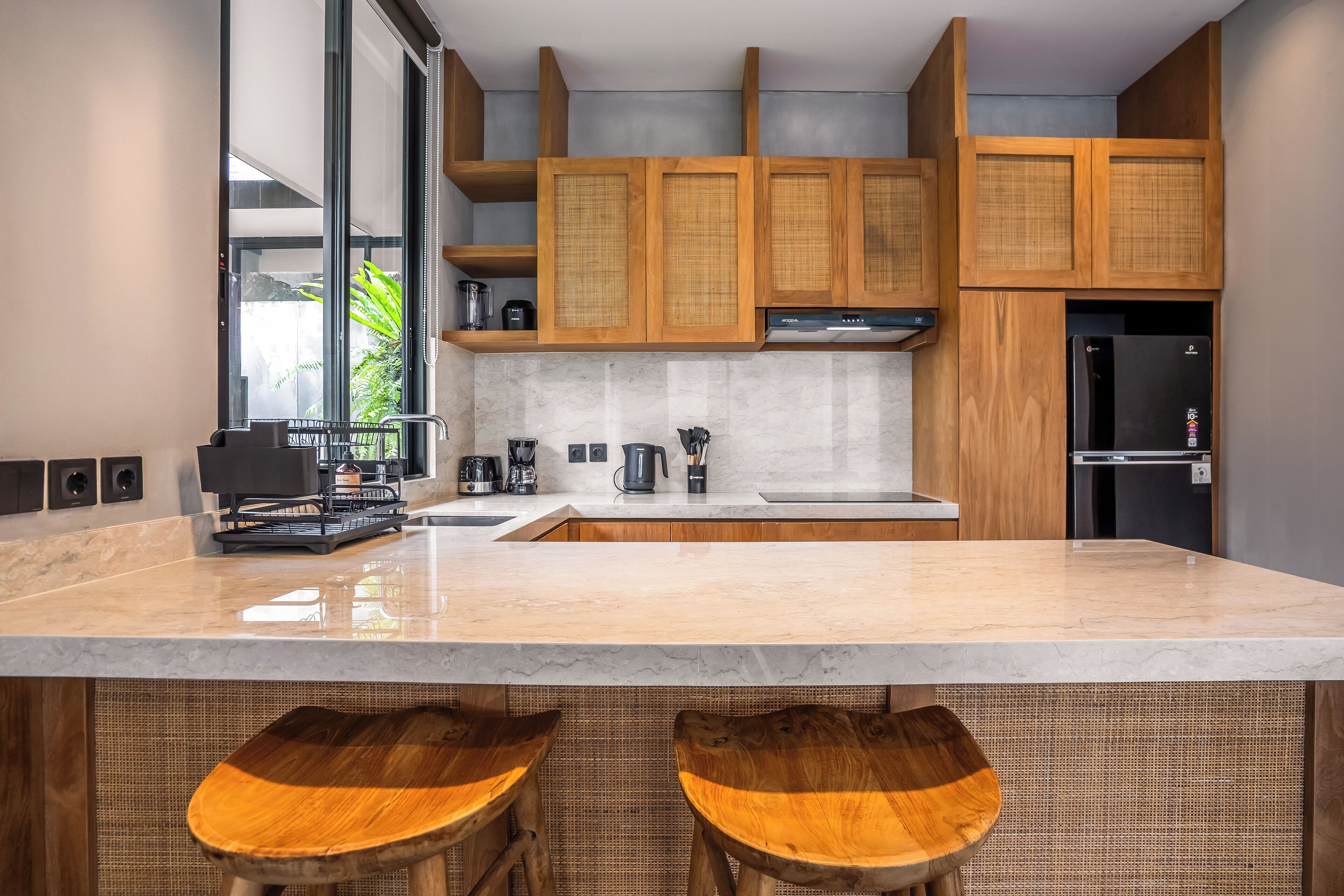 Una cocina moderna con armarios de madera, encimera de mármol y dos taburetes de madera.