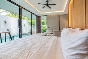 A modern hotel room with a large bed, a ceiling fan, and a view of a swimming pool. - Titi House Villa By Betterplace (Ubud)