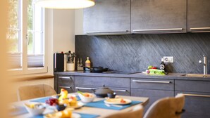 Una cocina moderna con armarios oscuros, una estufa a gas y una zona de comedor con una mesa puesta para comer.