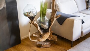 Una habitación con un sofá blanco, una mesa de vidrio con adornos y una escultura de madera singular.